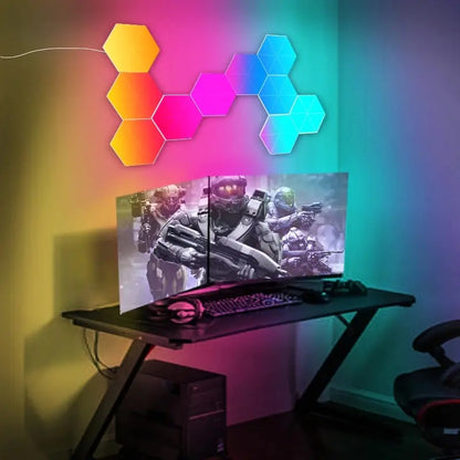Colorful hexagon LED wall lights arranged above a gaming desk with triple monitors and a keyboard