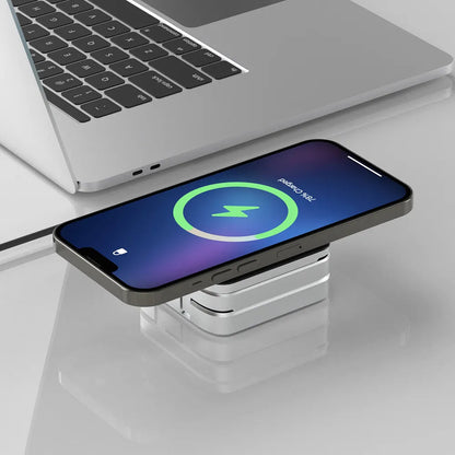 Multi-device charging station wirelessly charging a smartphone next to a silver laptop on a white desk