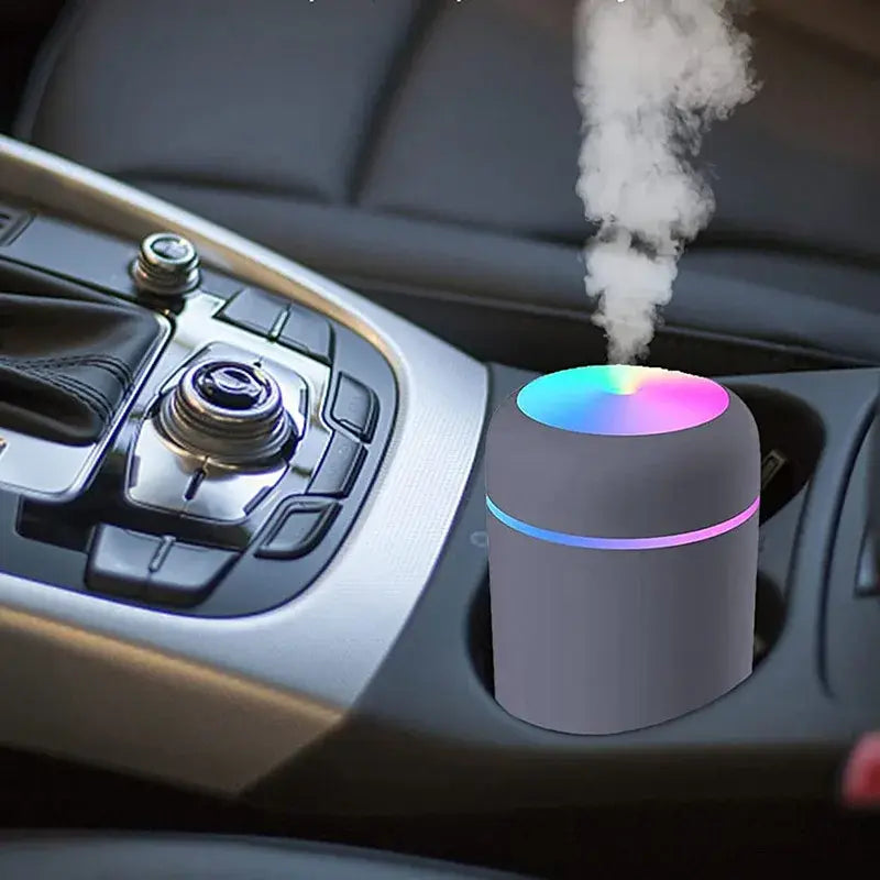 Portable mini air humidifier with colorful LED light placed in car cup holder releasing mist